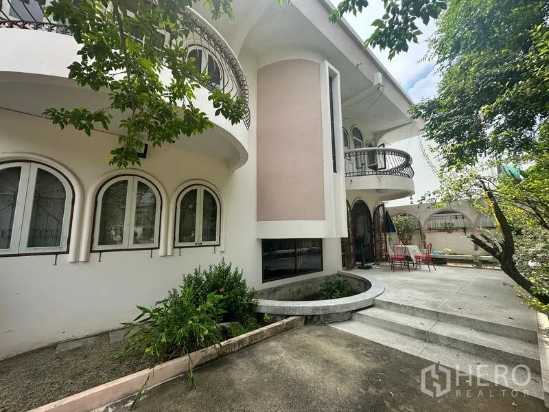 Detached House for sale in Phra Khanong, Bangkok - Front facade showcasing rounded balconies, steps and planted beds along the driveway.