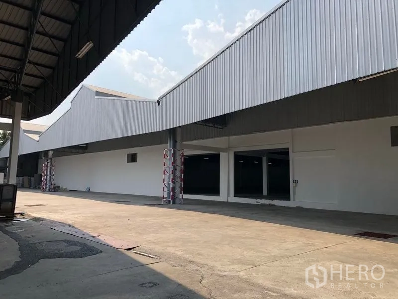 คลังสินค้า ให้เช่าในPak Kret, Nonthaburi - ด้านหน้าโกดังทรงจั่วพร้อมหลังคาคลุมลานโหลดและถนนคอนกรีตกว้าง