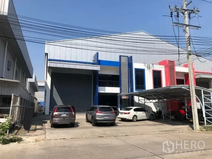 工厂 出租或出售在Bang Phli, Samut Prakan - 邦披现代工厂外观，设大型卷闸门、金属立面与现场停车位。