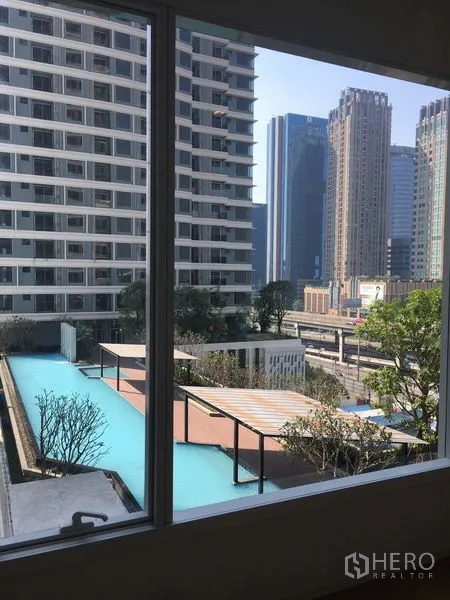 Condominium for rent or sale in Chatuchak, Bangkok - Window view of the condo’s pool deck and nearby high-rise city skyline.