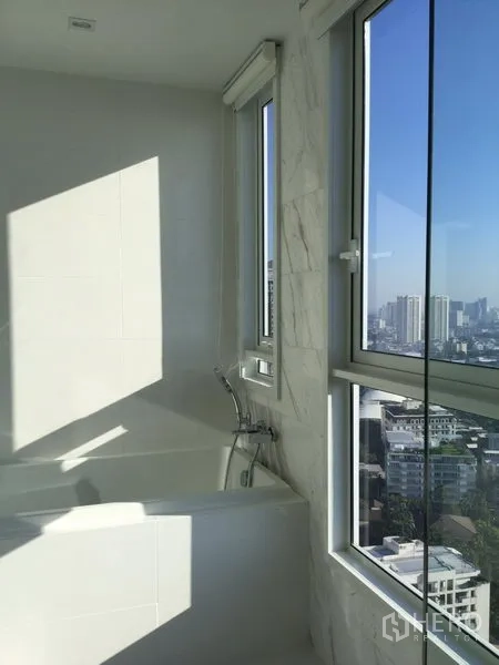 公寓 出租或出售在Watthana, Bangkok - 浴室设靠窗浴缸，可俯瞰曼谷城市天际线。