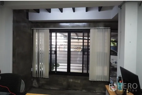 Home Office for rent in Lat Phrao, Bangkok - Office window with vertical blinds and industrial-style concrete walls.