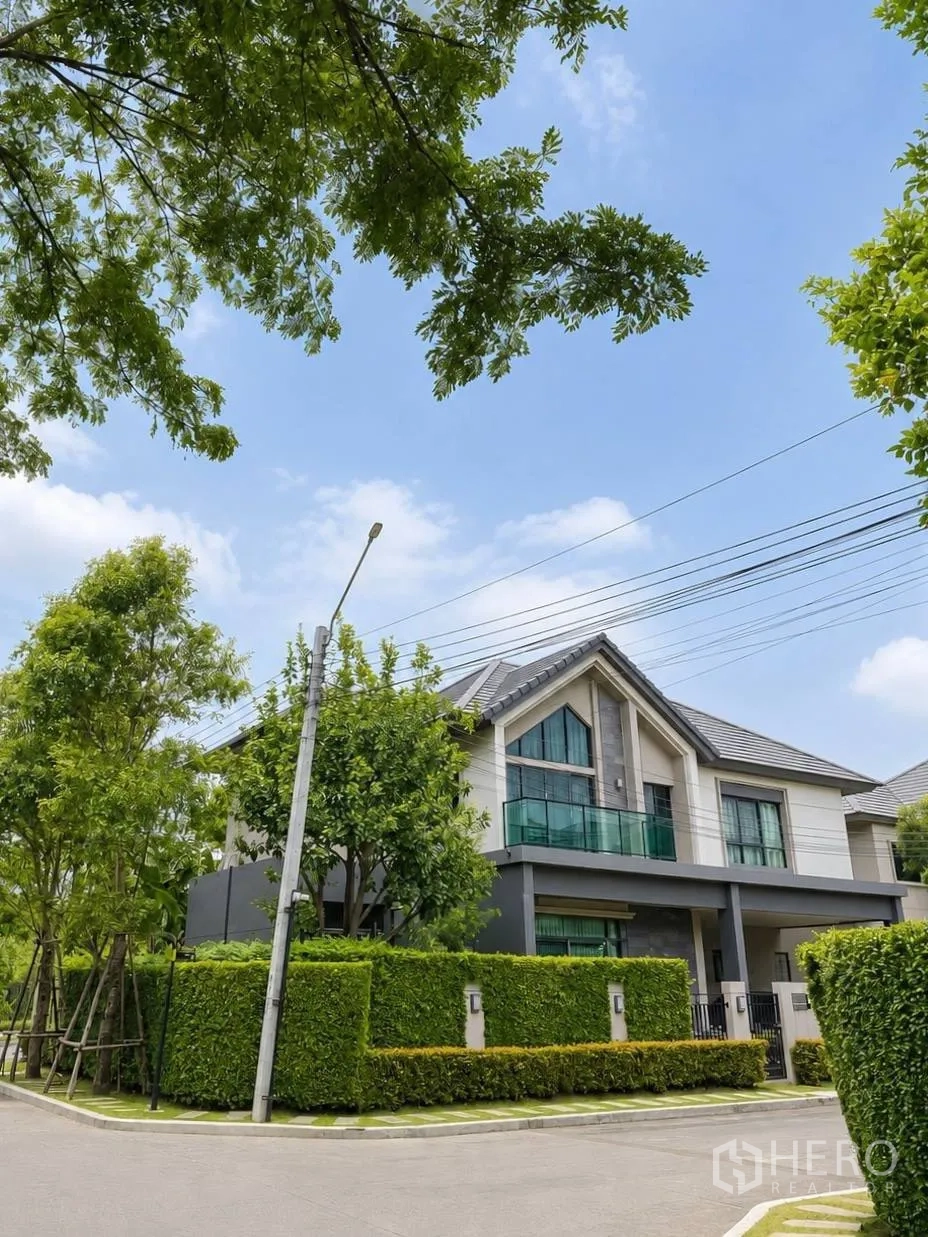 บ้านเดี่ยว for sale in Bang Kruai, Nonthaburi - มุมมองถนนของบ้านเดี่ยวสมัยใหม่ ล้อมด้วยแนวไม้พุ่มตัดแต่ง