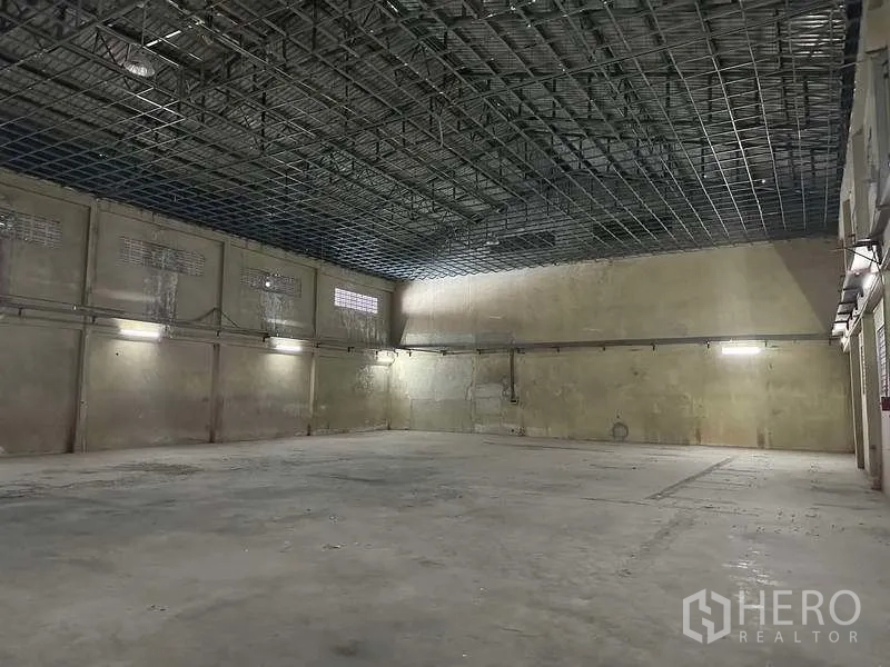 Factory for rent or sale in Bang Phli, Samut Prakan - Warehouse space with high grid ceiling, concrete walls and bright fixtures.