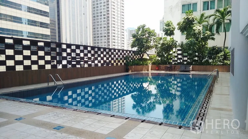公寓 出售在Watthana, Bangkok - 室外游泳池与池畔平台，背景为城市高楼与绿植。