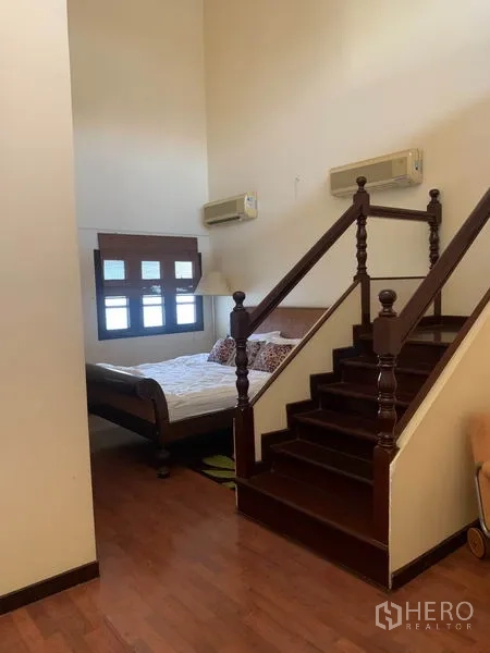 联排别墅 出租或出售在Phra Khanong, Bangkok - 分层卧室，短木楼梯通往休息区，木地板与空调。
