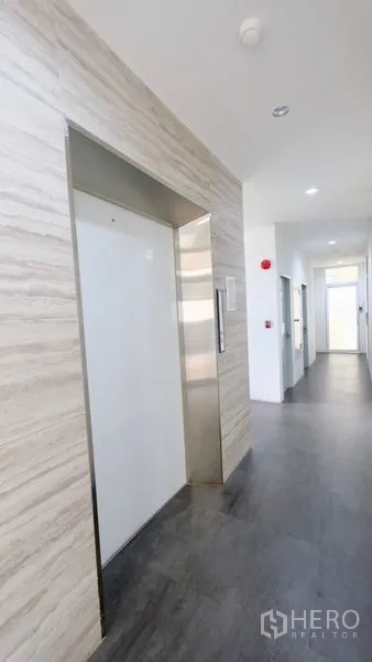 Office Space for rent in Bang Rak, Bangkok - Clean elevator lobby with stone wall cladding and grey flooring in a modern office building.
