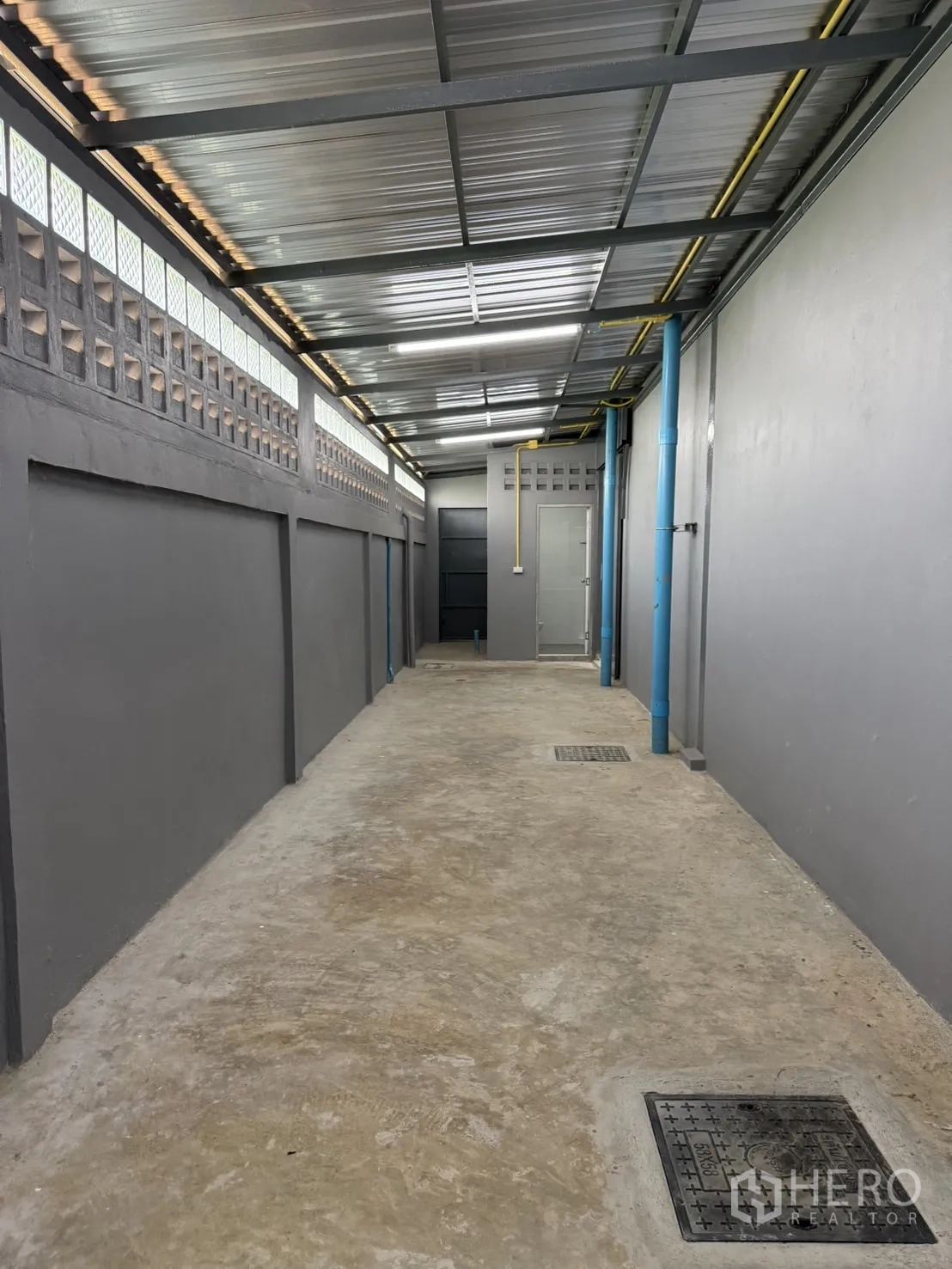 Warehouse for rent in Lam Luk Ka, Pathum Thani - Covered side service corridor with drains and utility pipes.