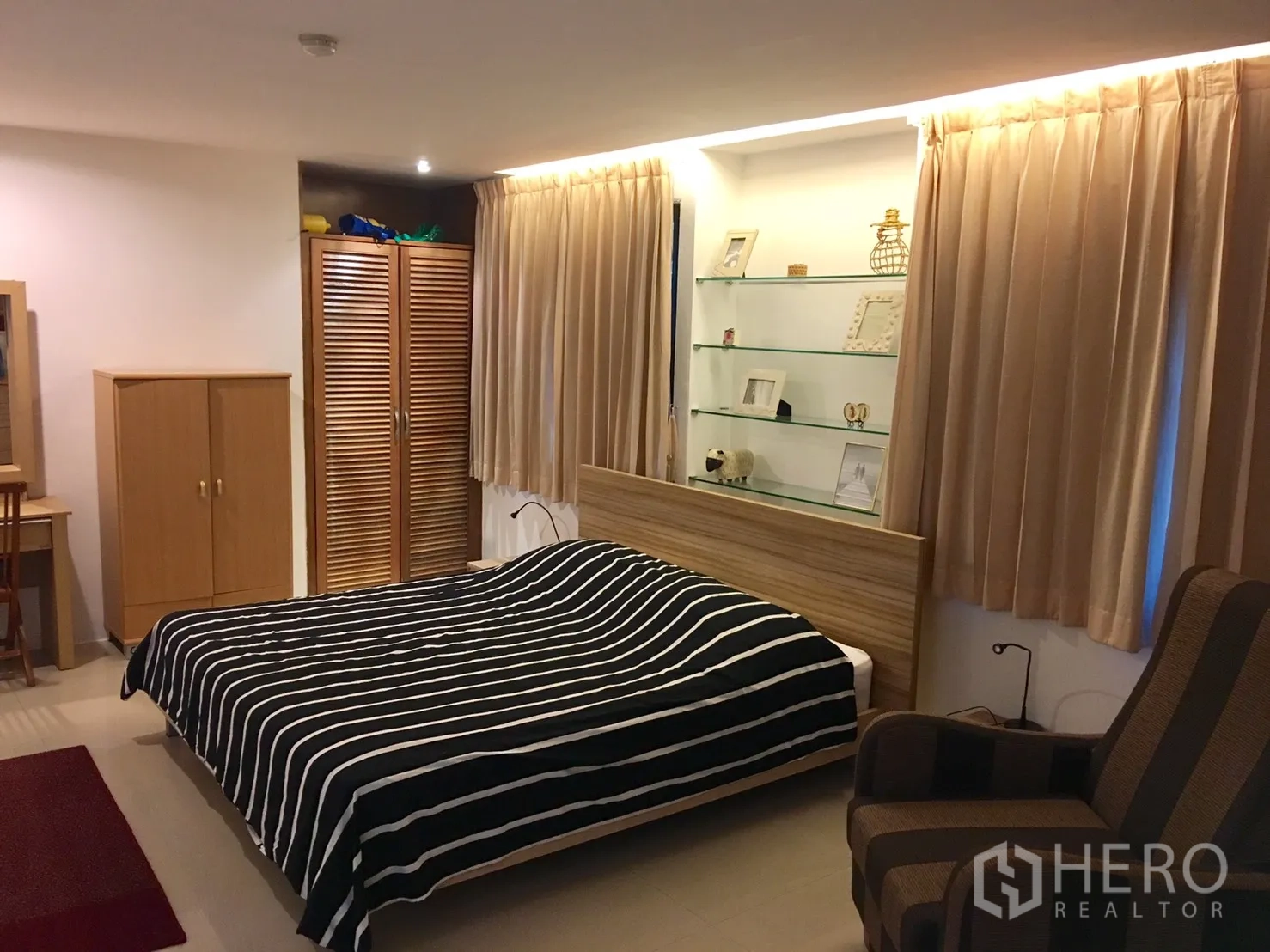 公寓 出租在Bang Rak, Bangkok - 宽敞次卧，条纹床品、衣柜与展示隔板。