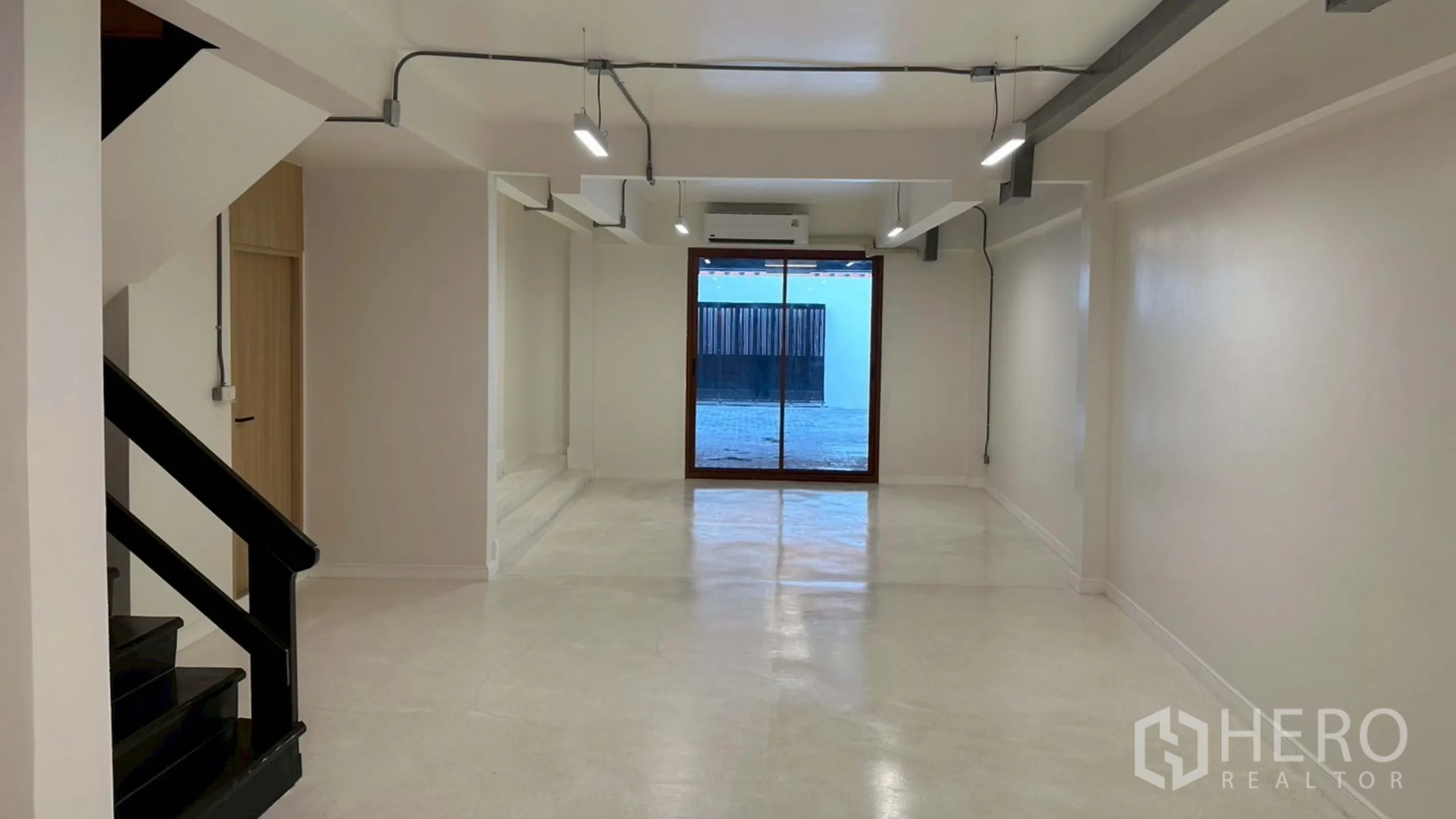 Home Office for rent in Watthana, Bangkok - Long open-plan room with sliding glass door and linear ceiling lights.