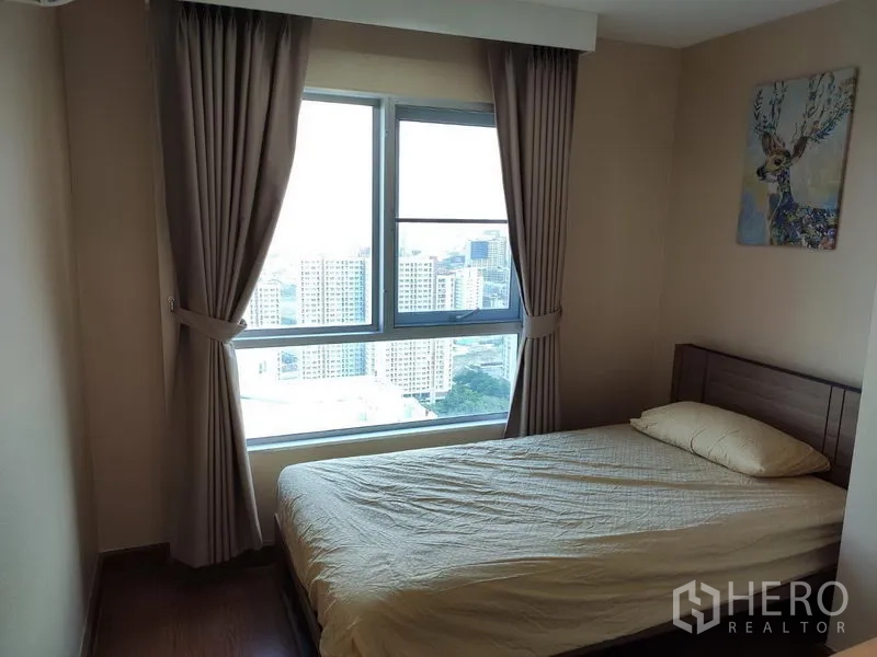 คอนโด ให้เช่าในHuai Khwang, Bangkok - ห้องนอนพร้อมหน้าต่างบานใหญ่เห็นวิวเมือง ผ้าม่านทึบ โทนสีอบอุ่น