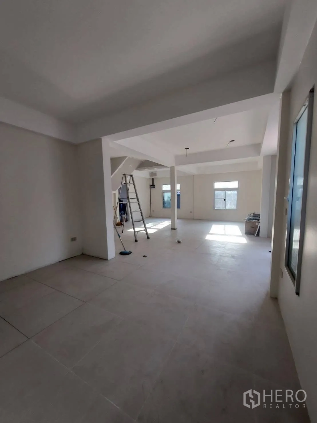 บ้านเดี่ยว for rent in Watthana, Bangkok - พื้นที่โอเพ่นสเปซชั้นล่างปูกระเบื้อง มีเสาและช่องแสงขณะเก็บงานตกแต่ง.
