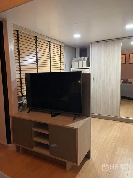 Condominium for rent in Ratchathewi, Bangkok - TV console facing sliding-door closet and study nook with wooden blinds.