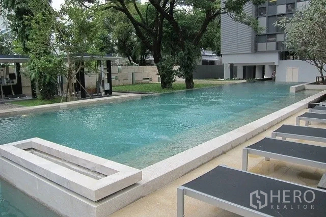 公寓 出租或出售在Watthana, Bangkok - 户外长泳池，配躺椅与绿树花园景观。