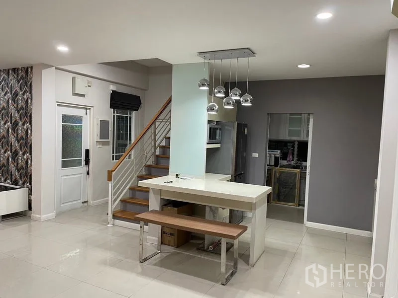 Detached House for rent in Bang Kapi, Bangkok - Open-plan kitchen with island, pendant lights, staircase and stainless refrigerator.