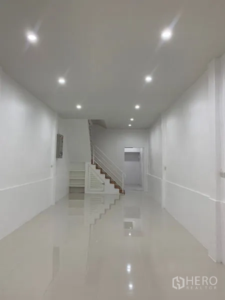 Townhouse for sale in Yan Nawa, Bangkok - Long open living hall with staircase and shiny tiled flooring.