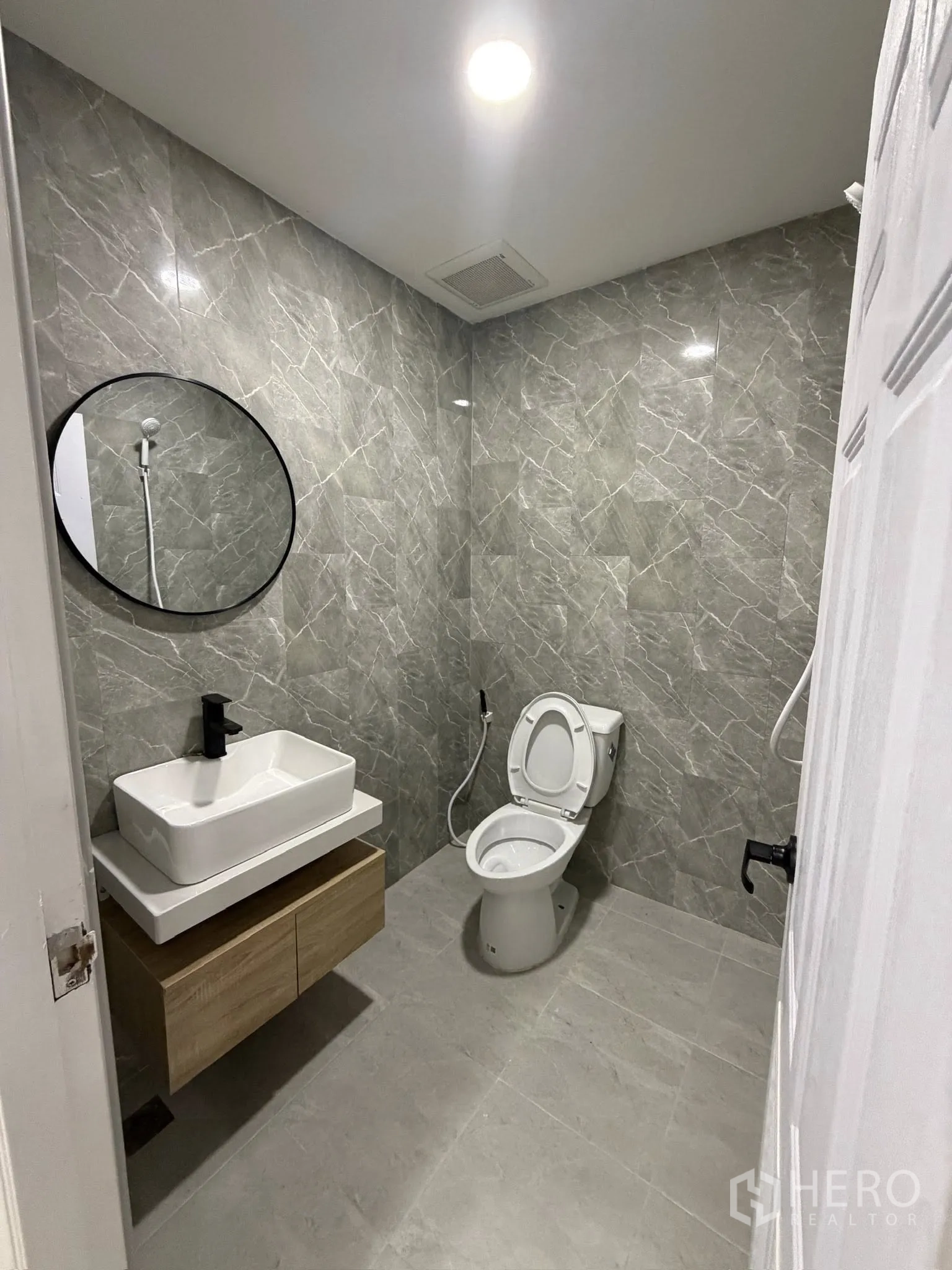 Townhouse for rent or sale in Yan Nawa, Bangkok - Modern bathroom with gray marble-look tiles, vanity, and toilet.