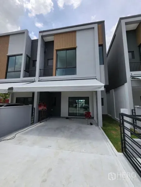 Townhouse for rent in Bang Phli, Samut Prakan - Contemporary two-storey townhouse facade with covered carport and sliding glass entrance.
