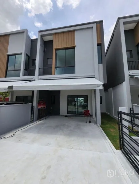 Townhouse for rent in Bang Phli, Samut Prakan - Contemporary two-storey townhouse facade with covered carport and sliding glass entrance.