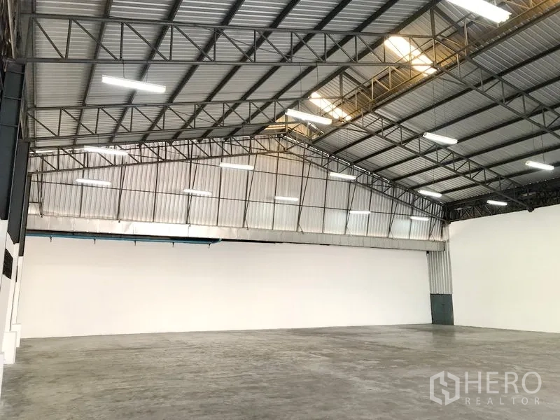 คลังสินค้า ให้เช่าในPak Kret, Nonthaburi - มุมมองเฉียงของฮอลล์เก็บสินค้าแบบโอเพ่นเพลน หลังคาจั่วสูง ไฟสว่าง และพื้นเรียบ
