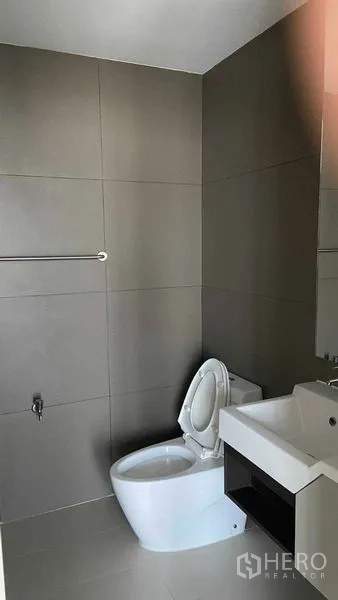 公寓 出租在Watthana, Bangkok - 极简卫浴，灰色瓷砖，悬空洗手台与现代坐便器。