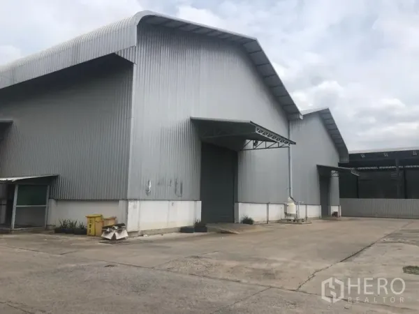 Factory for rent in Khlong Luang, Pathum Thani - Steel-clad factory exterior with high gable roof, loading bay and wide driveway in Khlong Luang.