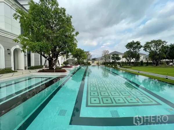Detached House for rent in Bang Phli, Samut Prakan - Long lap pool with geometric tiles framed by trees and lawn.