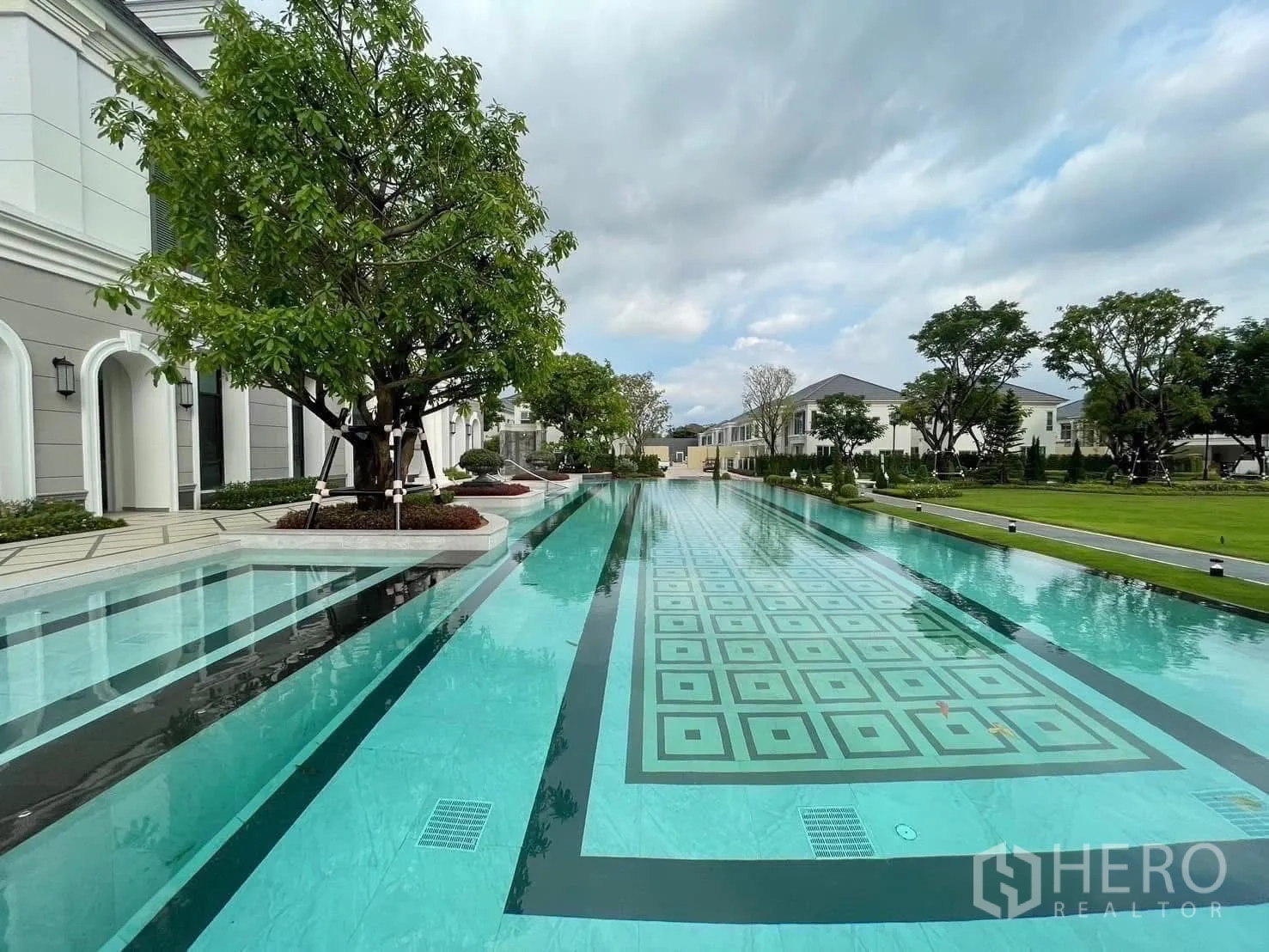 Detached House for rent in Bang Phli, Samut Prakan - Long lap pool with geometric tiles framed by trees and lawn.