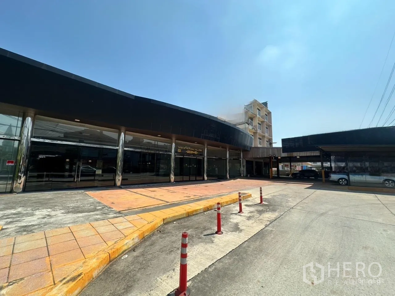 Showroom for rent in Suan Luang, Bangkok - Angled view of the showroom facade with drive-up area, bollards, and sidewalks.