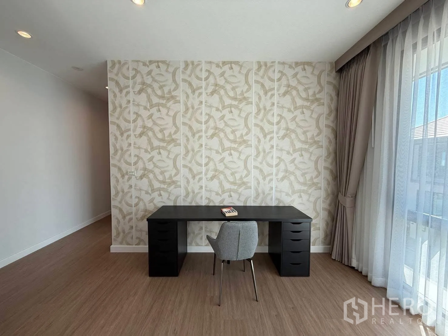 独栋房屋 for rent in Bang Phli, Samut Prakan - 工作区，黑色书桌、灰色椅子和装饰墙纸，旁有高窗。