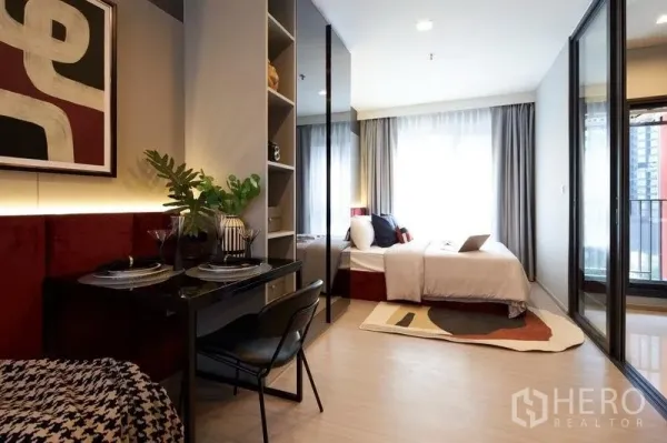 公寓 出售在Ratchathewi, Bangkok - 开间格局，书桌、床与通往阳台的推拉门。