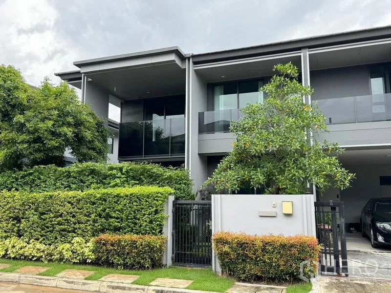 Detached House for rent in Bang Kapi, Bangkok - Street‑side view of the contemporary detached home with manicured hedge and secure gate.