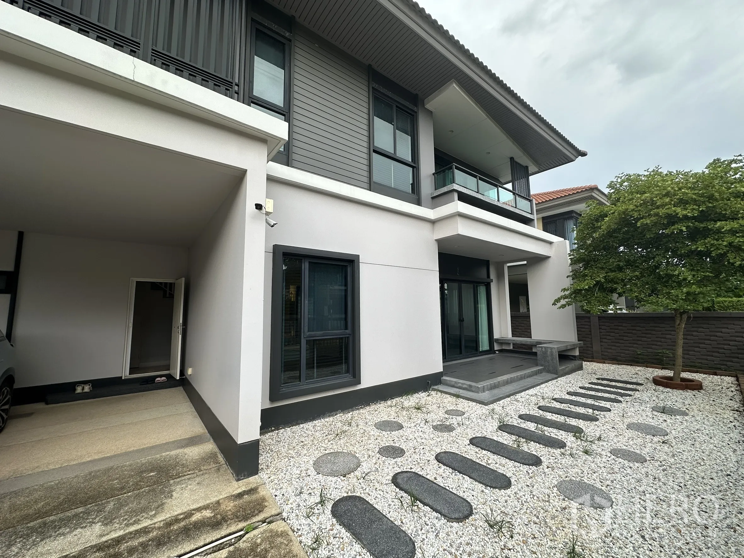 Detached House for rent in Lam Luk Ka, Pathum Thani - Front garden with white gravel, stepping stones and carport.