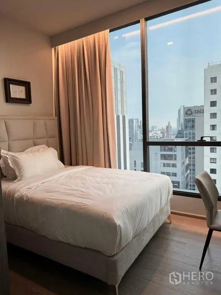 คอนโด ให้เช่าในWatthana, Bangkok - ห้องนอนรอง หัวเตียงบุผ้า โต๊ะทำงาน และหน้าต่างสูงวิวเมือง.