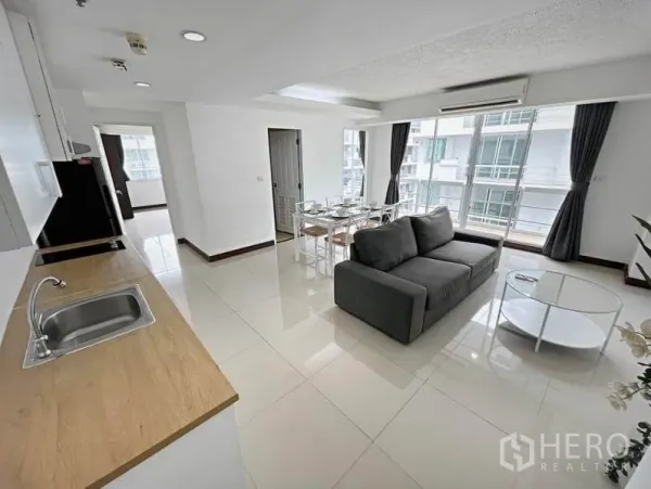 公寓 出租在Khlong Toei, Bangkok - 明亮的开放式客餐厅，灰色沙发、六人餐桌和大落地窗。