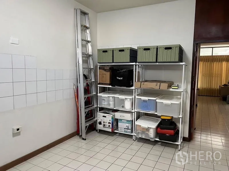 Townhouse for sale in Suan Luang, Bangkok - Utility room with tiled floor and wall, metal shelving for storage and a ladder.