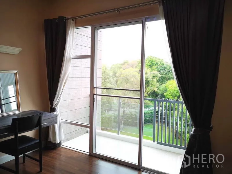 Townhouse for rent in Suan Luang, Bangkok - Private balcony with sliding glass doors overlooking green community views.