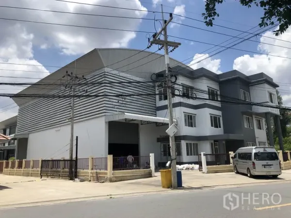 คลังสินค้า ให้เช่าหรือขายในLam Luk Ka, Pathum Thani - ภาพมุมถนนของโกดังสมัยใหม่พร้อมอาคารสำนักงาน 3 ชั้น ประตูรั้วและทางเข้าโหลดสินค้า ลำลูกกา