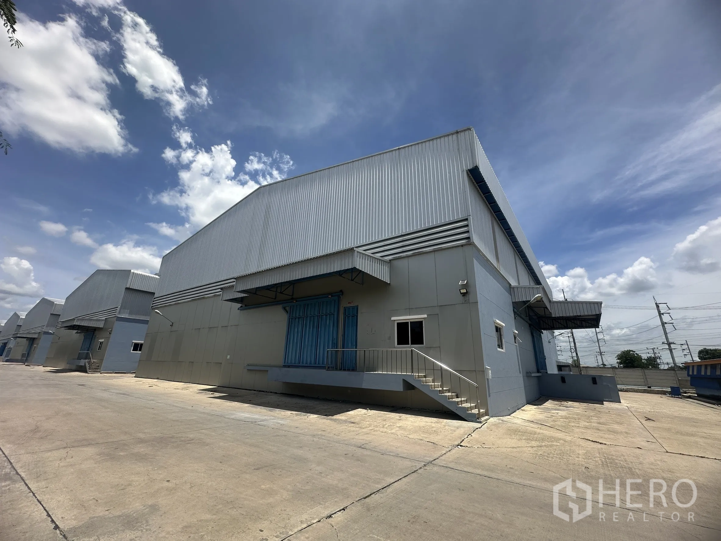 โกดัง for rent in Lat Lum Kaeo, Pathum Thani - อาคารโกดังหลายยูนิตพร้อมกันสาดและช่องขนถ่ายสินค้าริมถนนภายในโครงการกว้าง