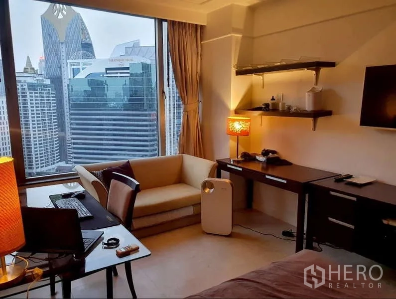 Condominium for sale in Pathum Wan, Bangkok - Work-from-home corner with desk and sofa beside a large window and skyline outlook