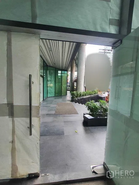 Retail Space for rent in Bang Rak, Bangkok - View from the shop doorway to a covered plaza with tiled walkway and planters.