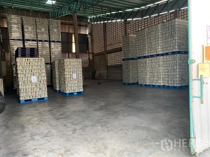 Warehouse for rent in Mueang Pathum Thani, Pathum Thani - Warehouse interior with high ceiling, ventilated brick walls, stacked pallets, and polished concrete floor.