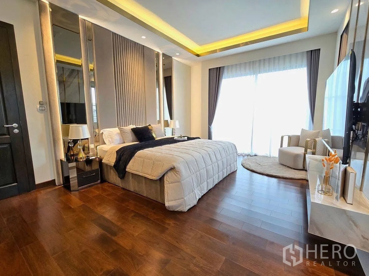 บ้านเดี่ยว for rent or sale in Bang Phli, Samut Prakan - ห้องนอนมาสเตอร์กว้างเตียงคิง ไฟซ่อน ฝ้าเพดาน พื้นไม้ และมุมนั่งเล่นริมหน้าต่างสูง