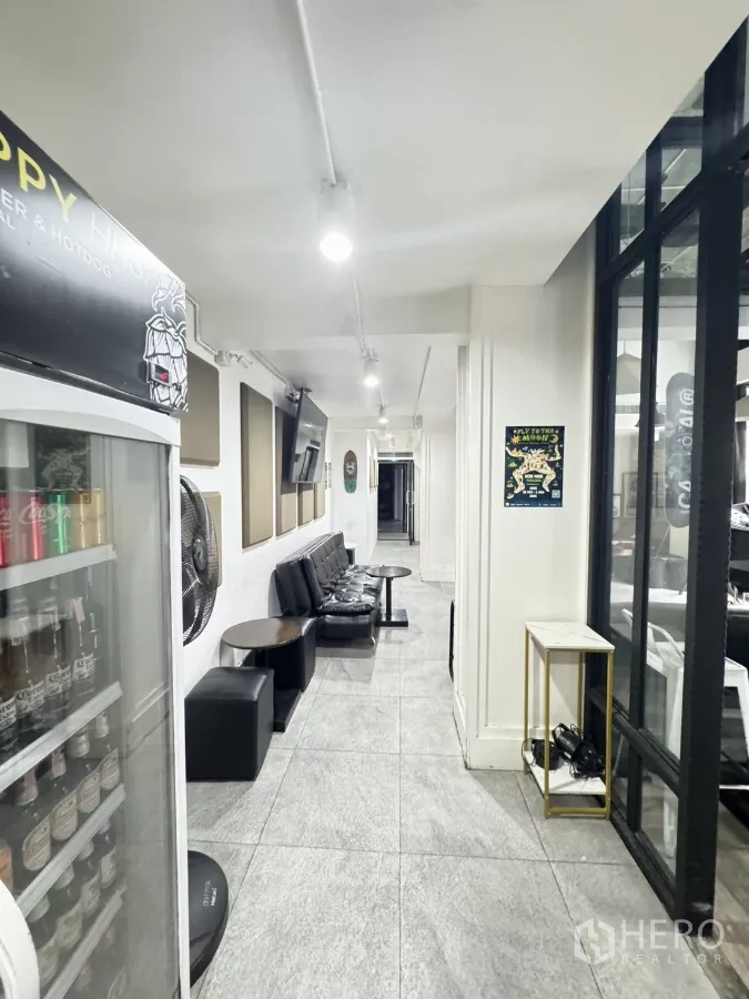 店屋 出租在Khlong Toei, Bangkok - 明亮走廊与等候区，皮质座椅、墙面电视及饮品冷柜。