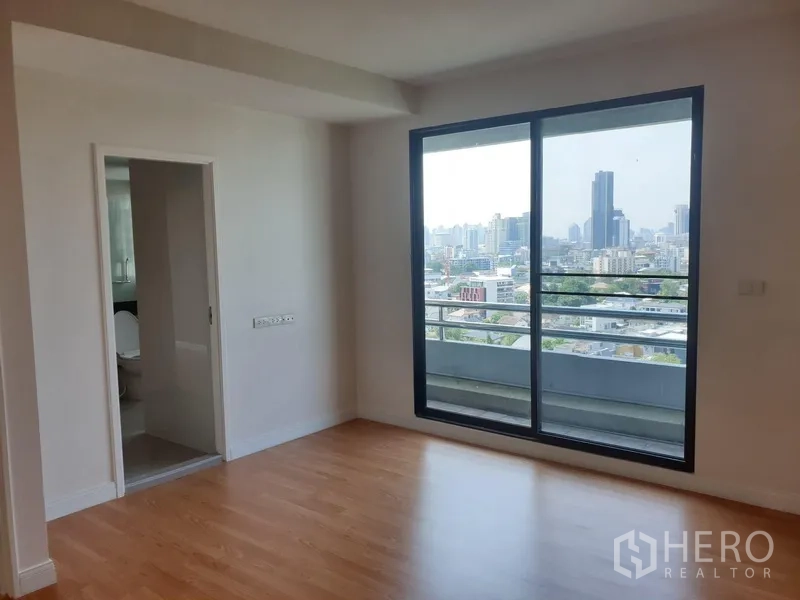 Condominium for rent in Watthana, Bangkok - Bedroom with ensuite access and sliding glass doors to a balcony overlooking the city.