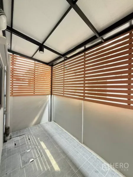 Townhouse for rent in Bang Phli, Samut Prakan - Covered utility terrace with privacy slat screens and gray tiled floor.