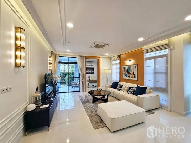 Detached House for rent or sale in Saphan Sung, Bangkok - Living room with TV console, sliding doors to a terrace and a neutral sofa set.