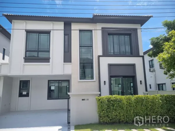บ้าน ให้เช่าในBang Phli, Samut Prakan - หน้าบ้านเดี่ยวสไตล์โมเดิร์น 2 ชั้น กระจกบานใหญ่ แนวรั้วพุ่มไม้ และที่จอดรถในร่ม ย่านบางพลี.