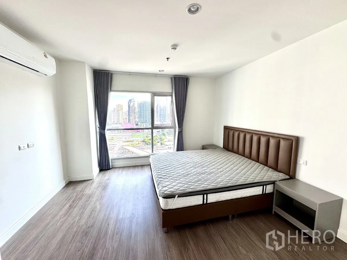 คอนโด for rent in Huai Khwang, Bangkok - ห้องนอนกว้างพร้อมหน้าต่างบานใหญ่ เตียง โต๊ะข้าง พื้นลามิเนต และแอร์