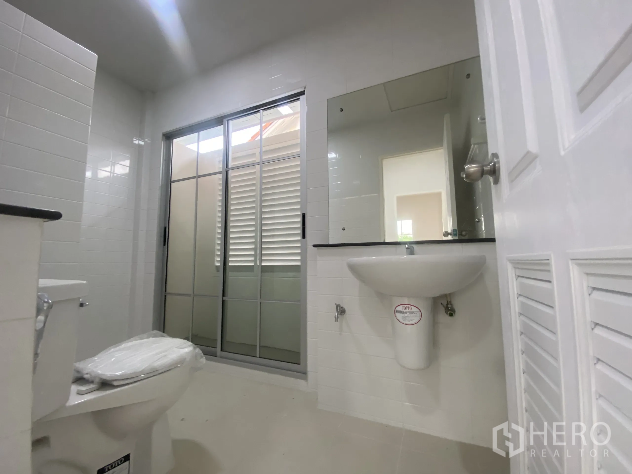 บ้าน ขายในNonthaburi - ห้องน้ำชั้นบนกระจกเงาบานใหญ่ โถสุขภัณฑ์ และประตูกระจกฝ้า.